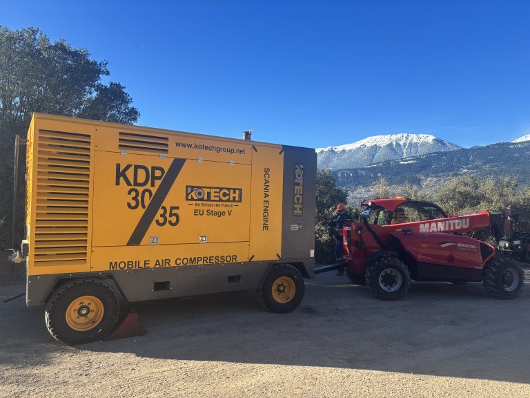 Kotech KDP-30/25 diesel portable air compressor operating alongside a DTH drilling rig at an open-pit iron ore mine in South Africa.